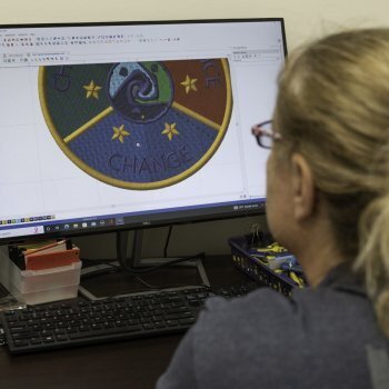 a woman observing an embroidery design on a computer screen